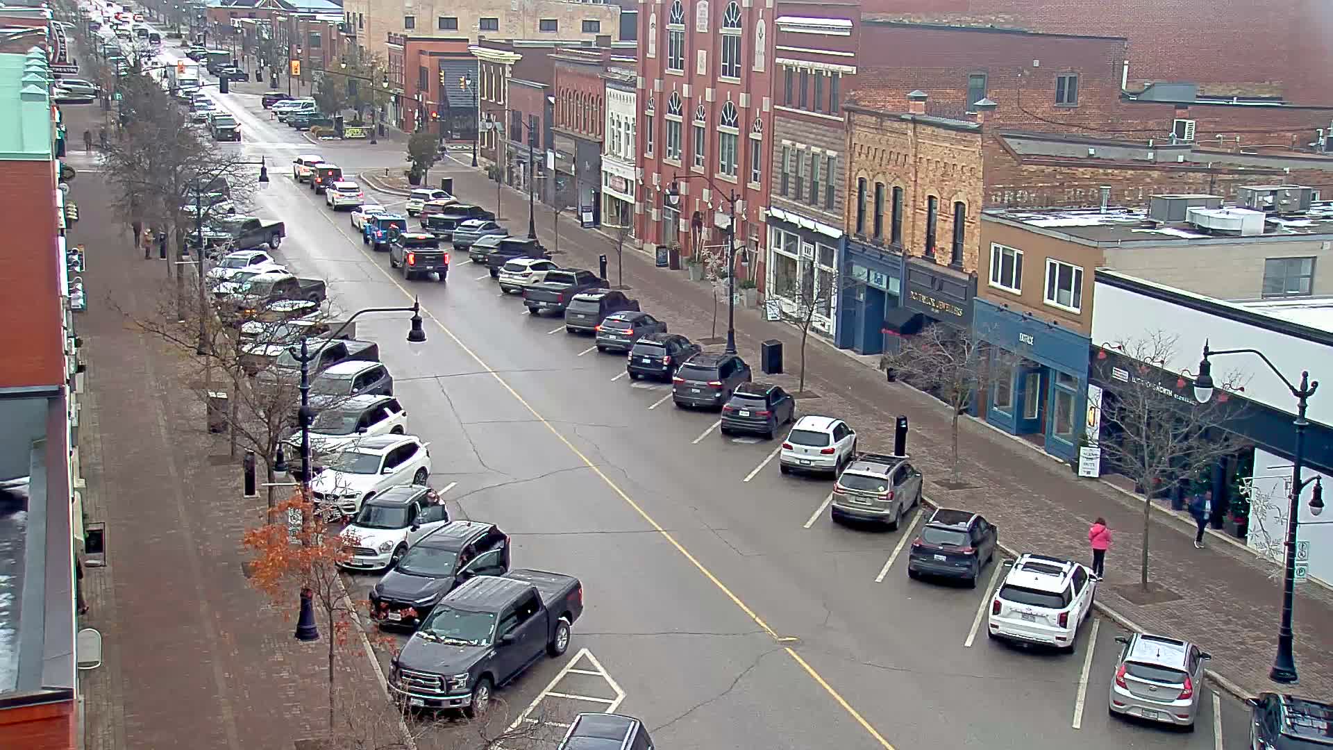 A mostly empty street at night, lined with two-story buildings and streetlights, under clear skies.
