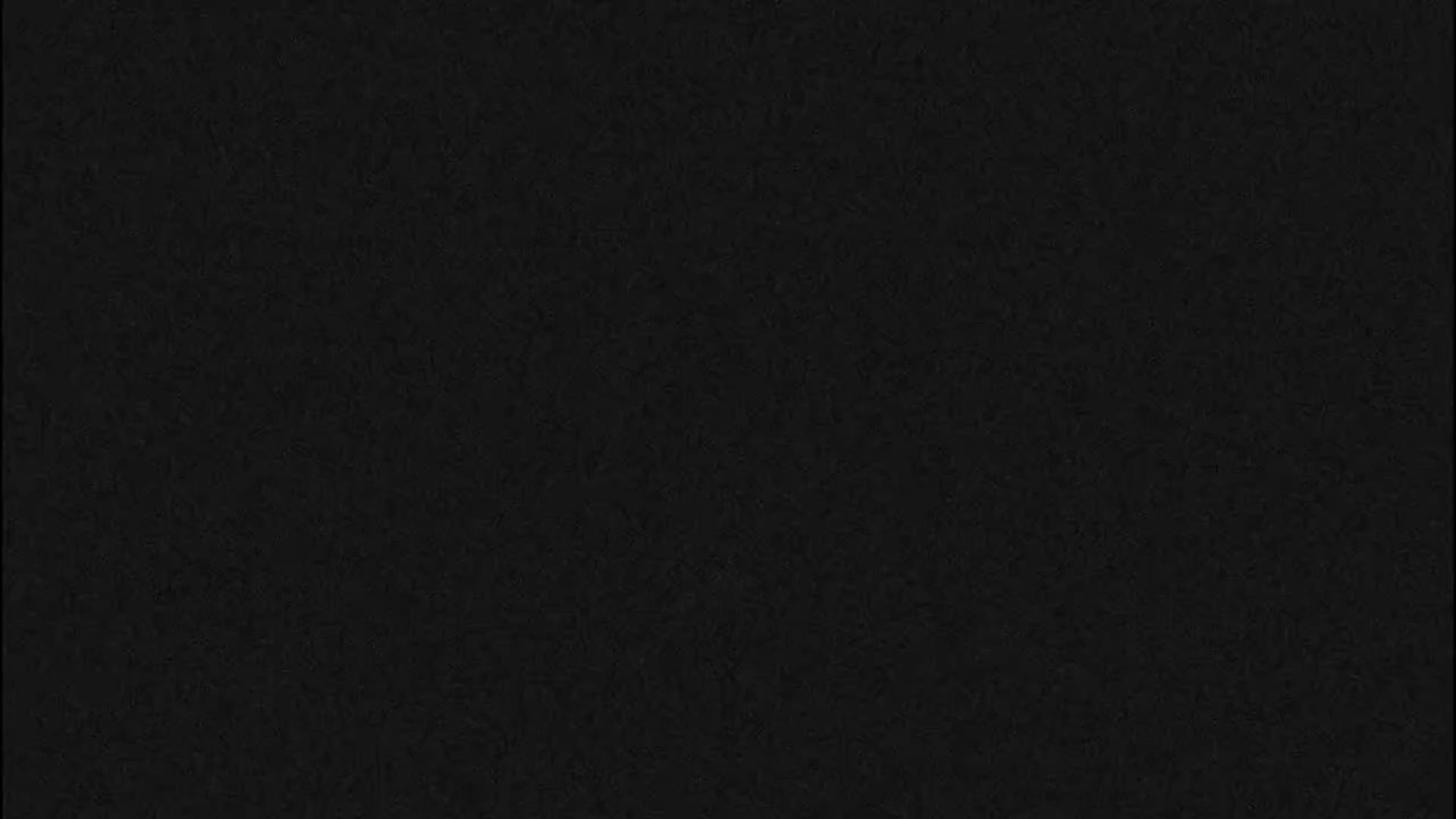 A wide, pink-tinged river is visible under a partly cloudy sky, with a paved pathway and grassy area in the foreground, featuring a few colorful Adirondack chairs.