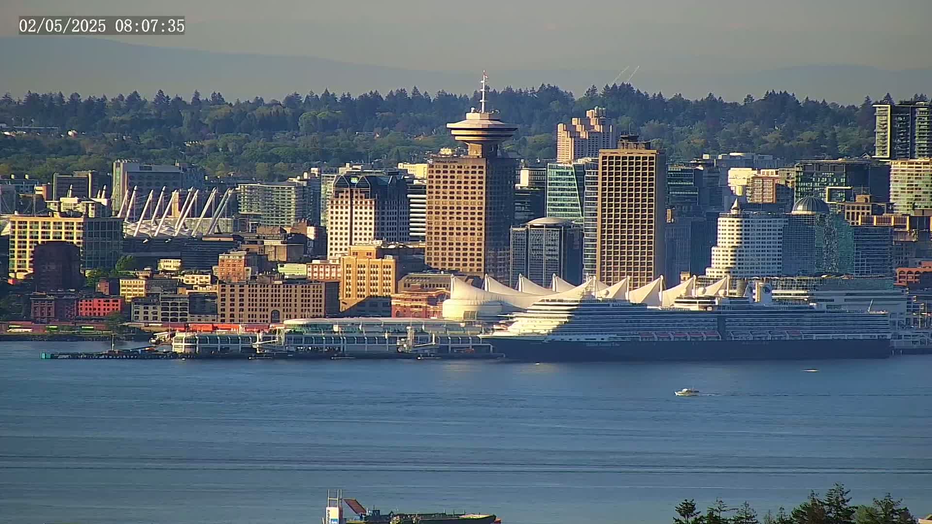 A cityscape with numerous high-rise buildings, a large cruise ship docked at a terminal, and a calm body of water under a clear sky.