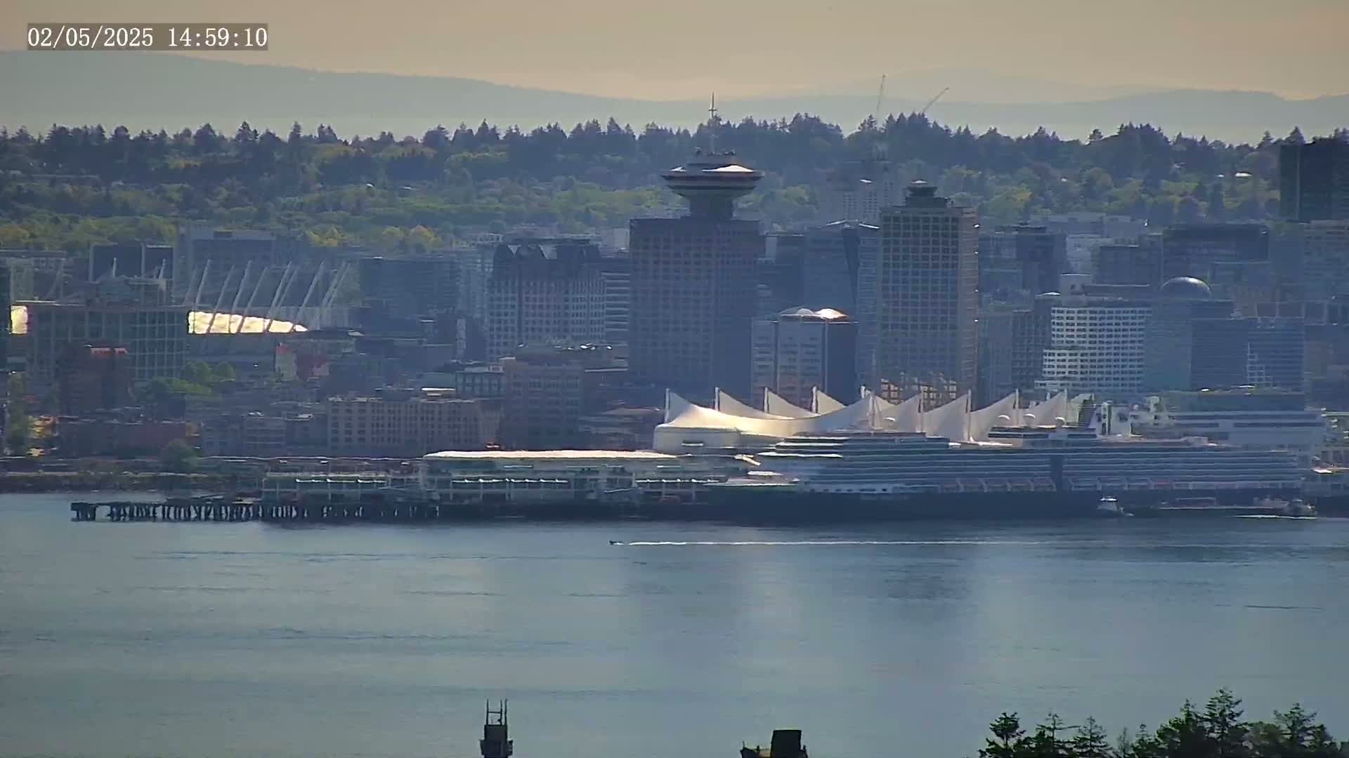A hazy view shows a city skyline with a cruise ship docked at a pier, all situated on a body of water.