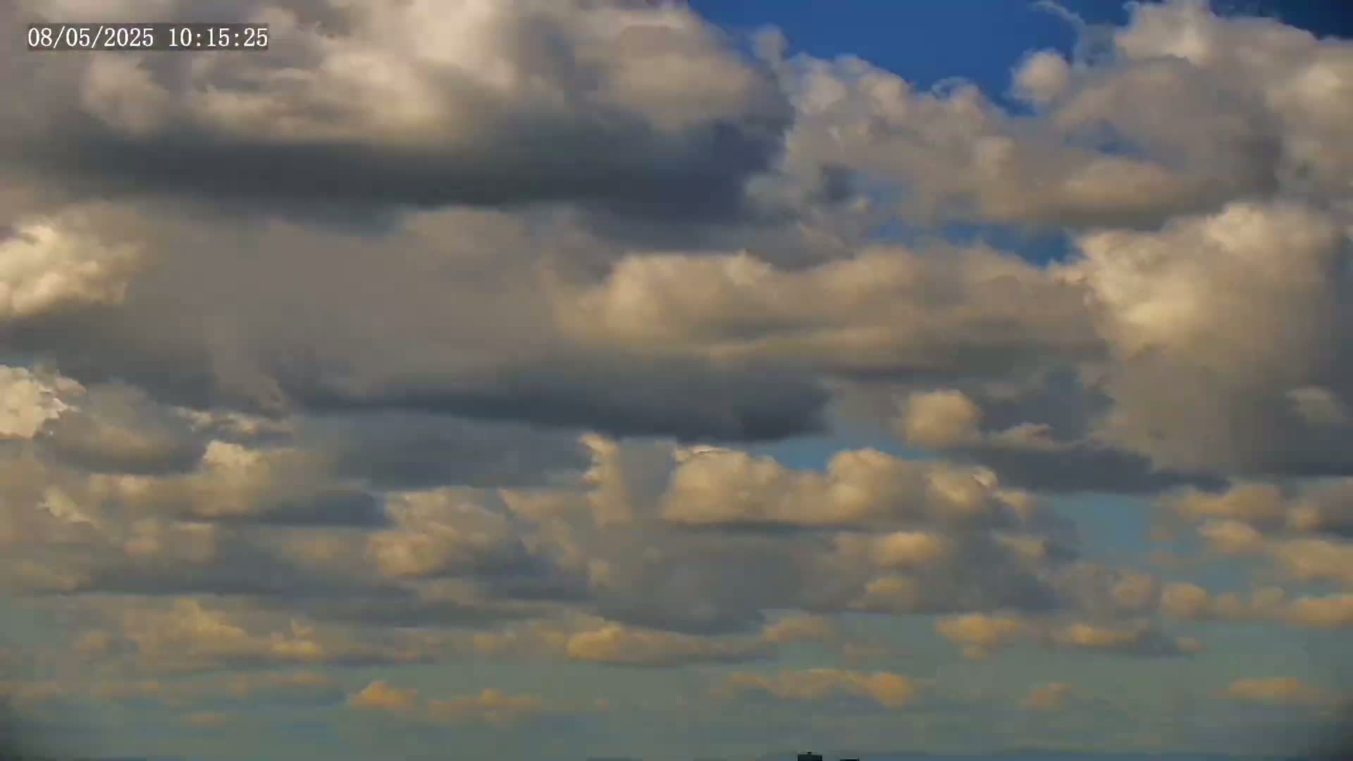 A mostly cloudy sky with puffy, light-grey and white cumulus clouds against a light blue sky.