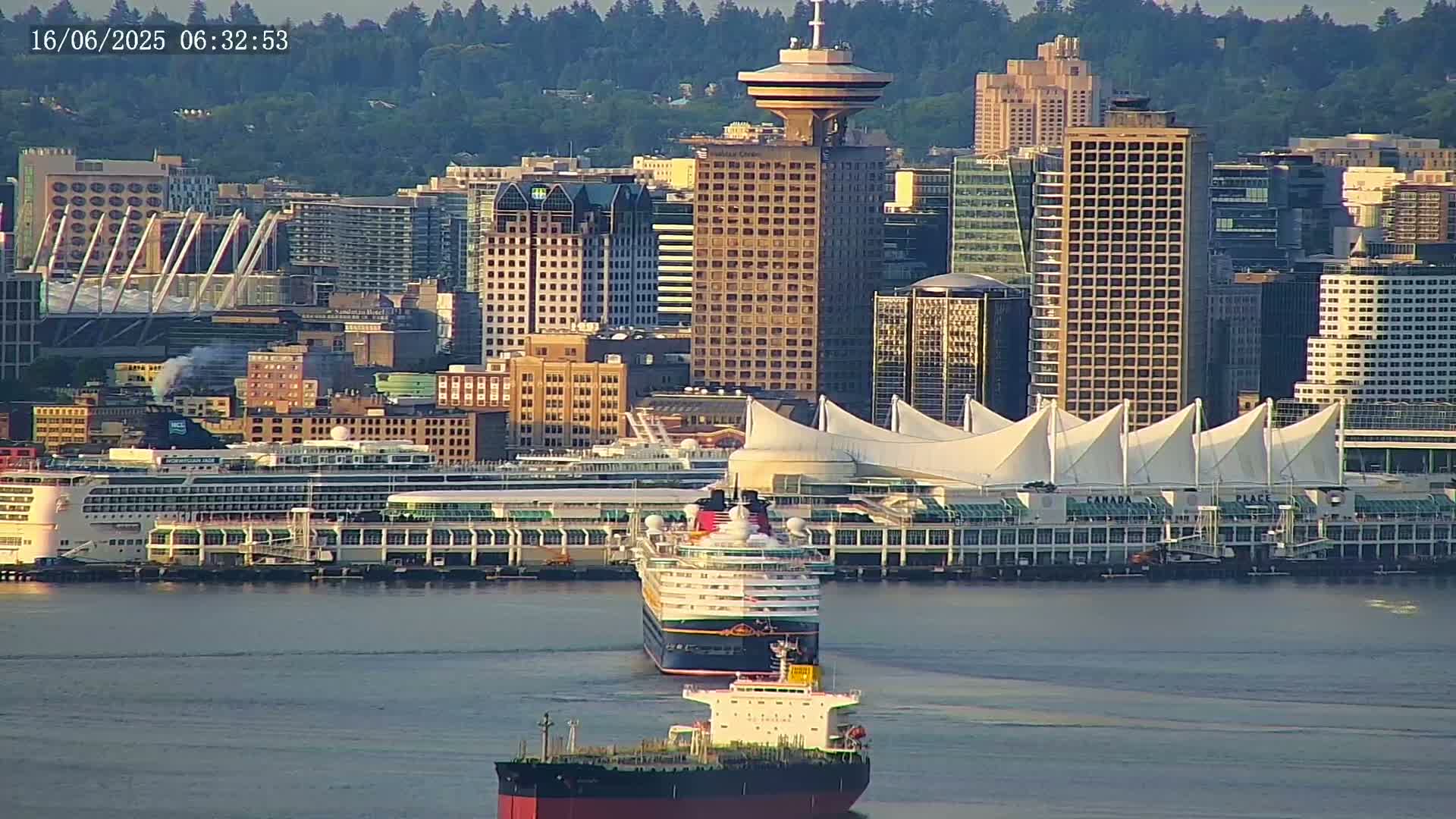 A waterfront city skyline with several skyscrapers and a cruise ship docked at a terminal, under a clear, sunny sky.