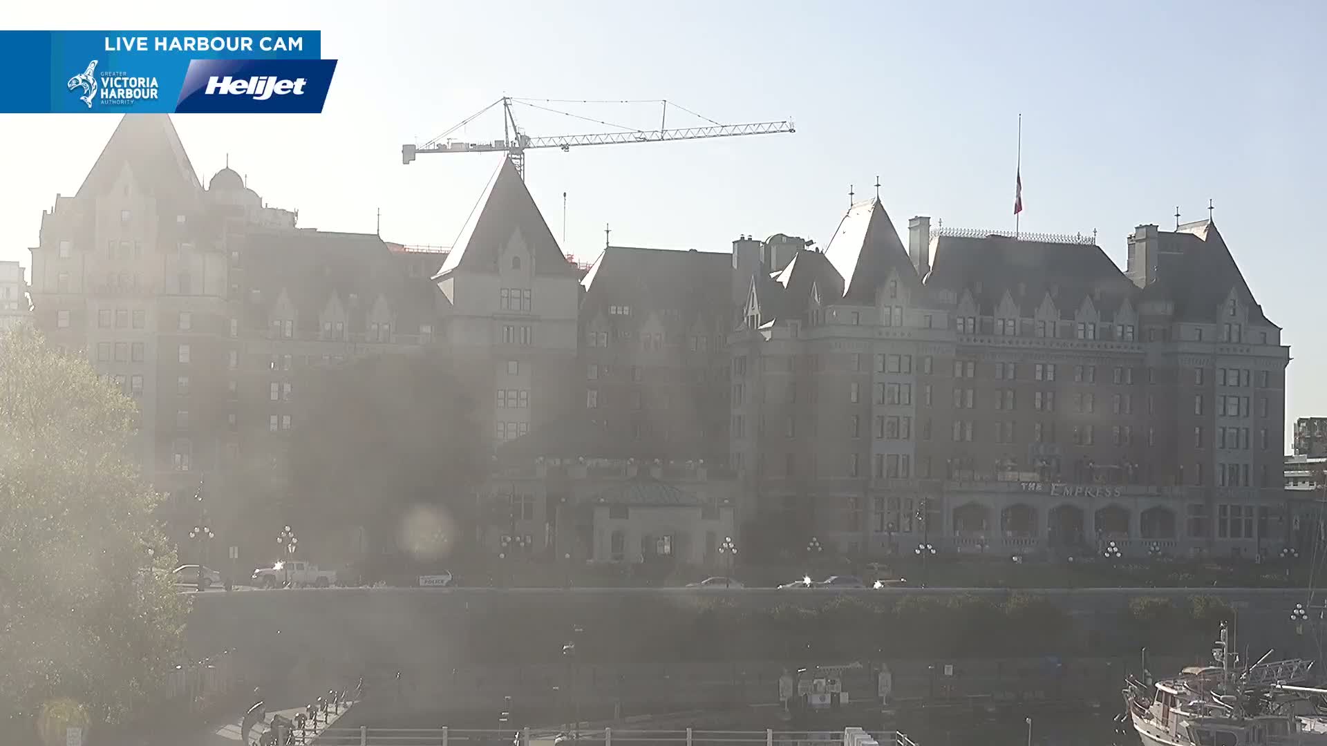 A large, historic hotel is visible on a hazy day, with a construction crane in the background.