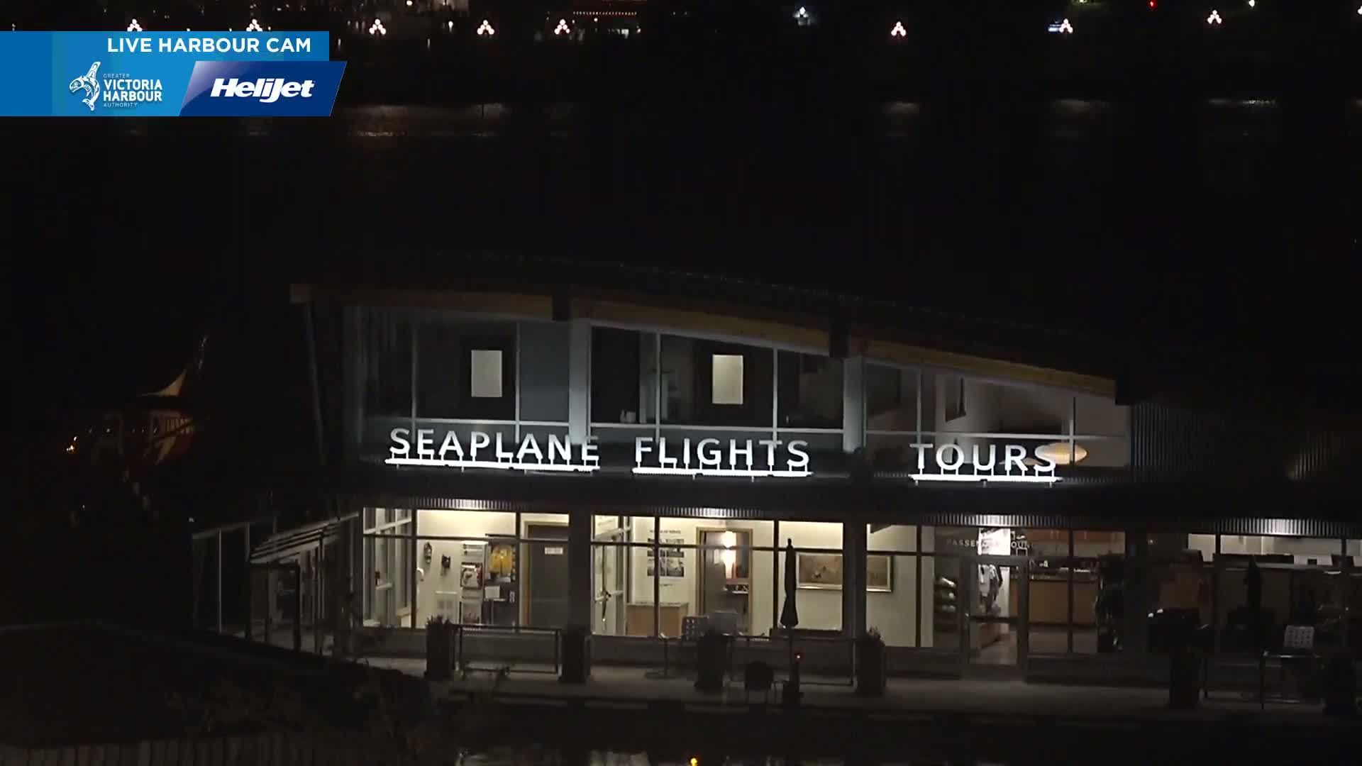 A brightly lit seaplane flights and tours building is visible at night.
