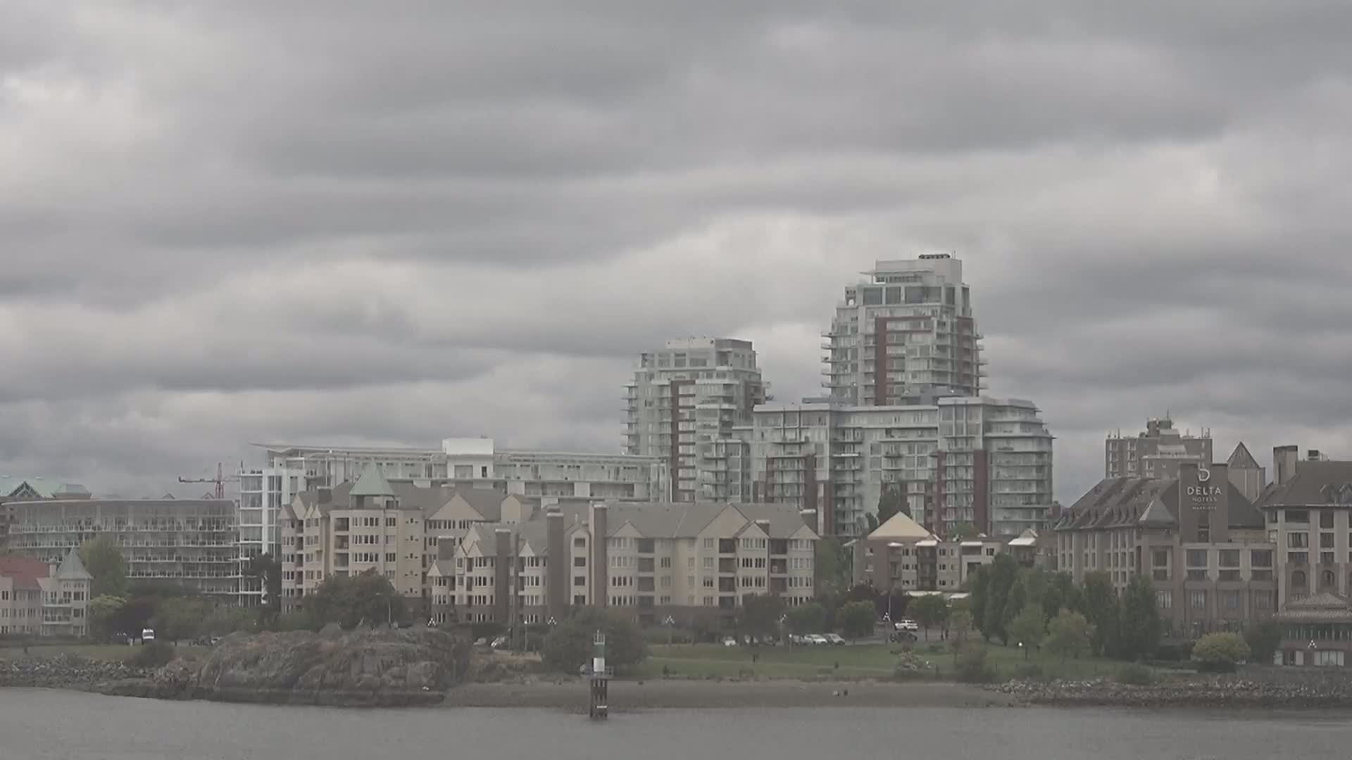 A waterfront scene of several multi-story residential buildings and a hotel under a heavily overcast sky.