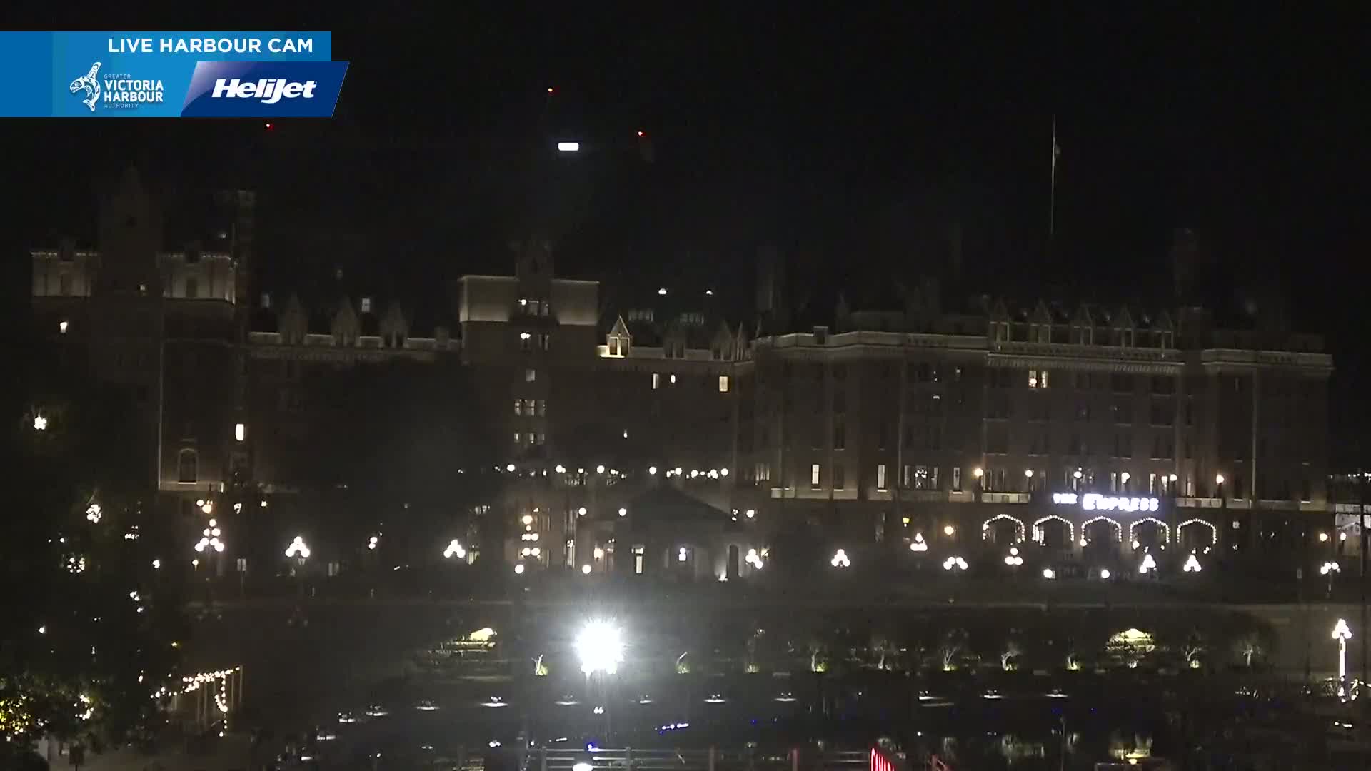 A large, dark-brown building with lights illuminating its exterior is seen at night.