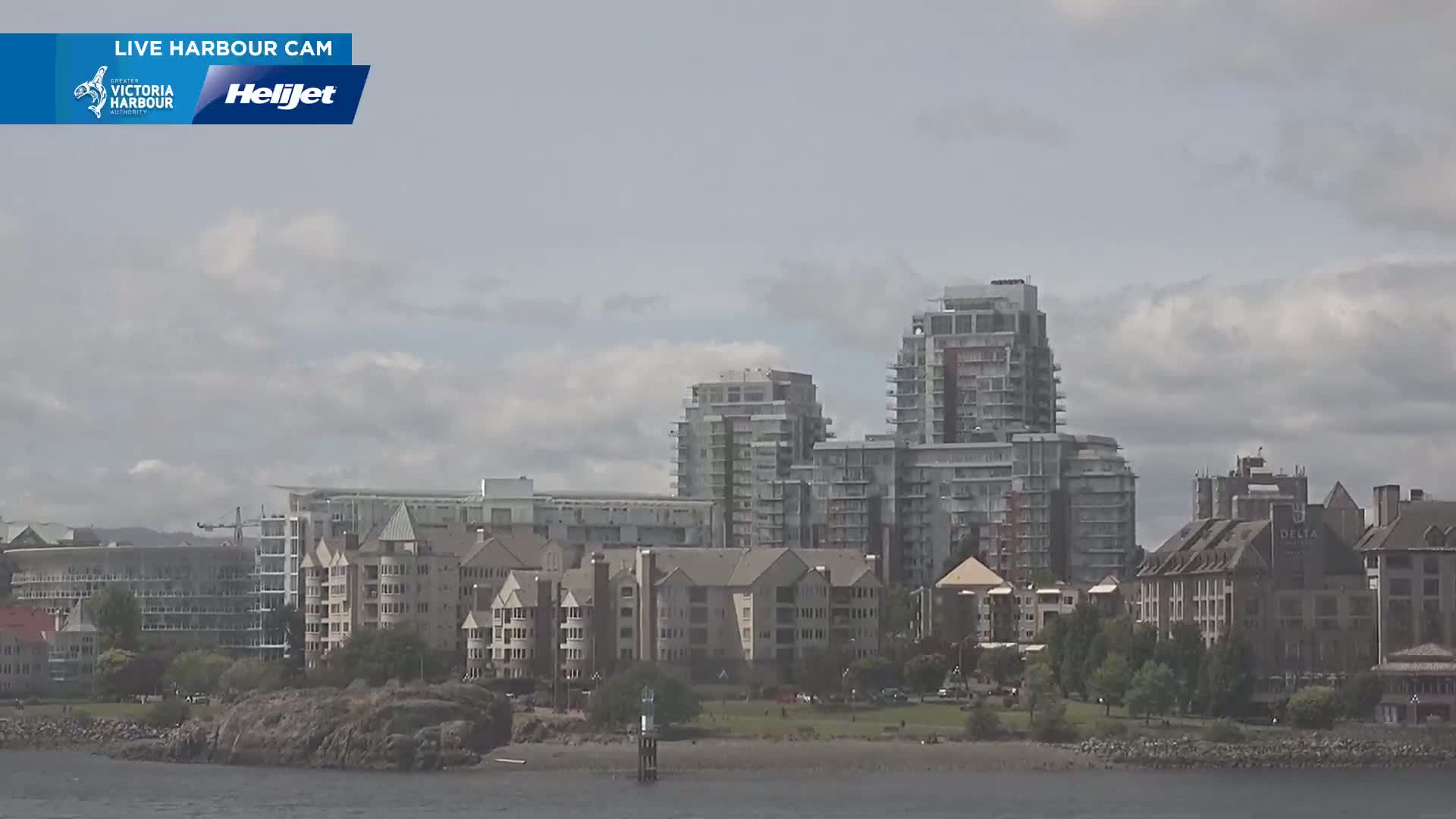 A waterfront view of several multi-story residential buildings and a hotel under a mostly cloudy sky.