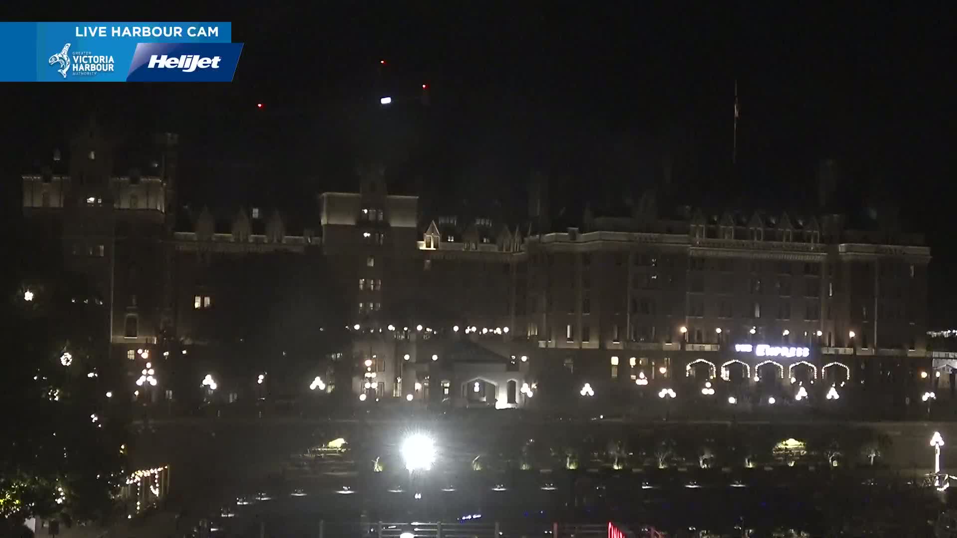 A large, dark-brown building with many lights is visible at night.