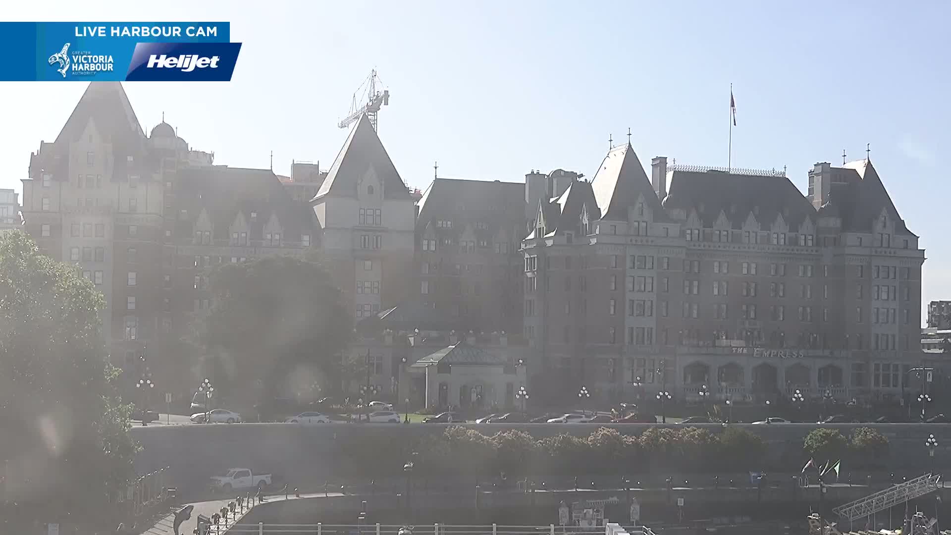 A hazy, sunny day reveals a large, historic hotel complex with a construction crane visible in the background.