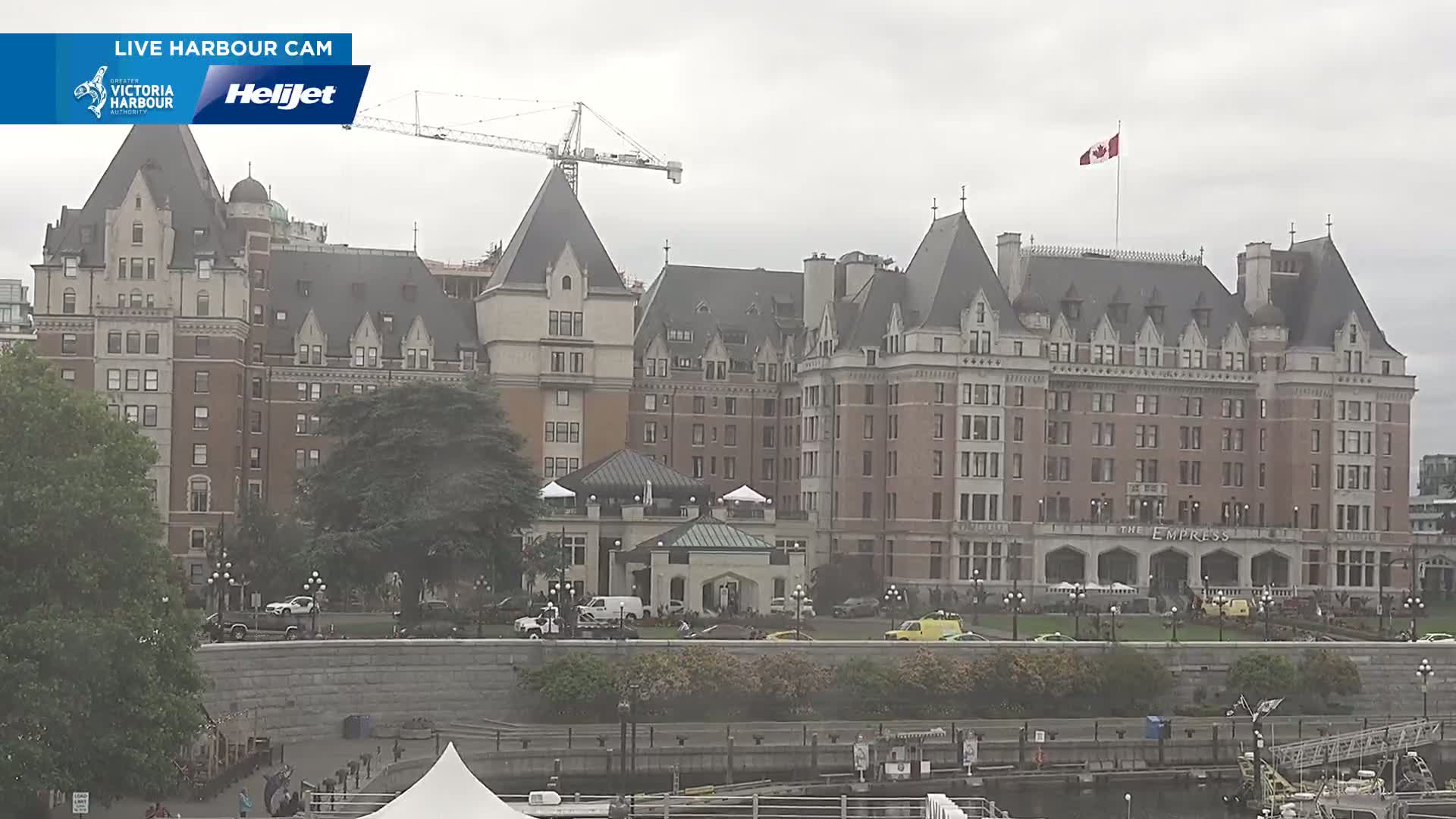 A large, brick hotel with many windows and a steeply pitched roof is visible on an overcast day, with a construction crane in the background.