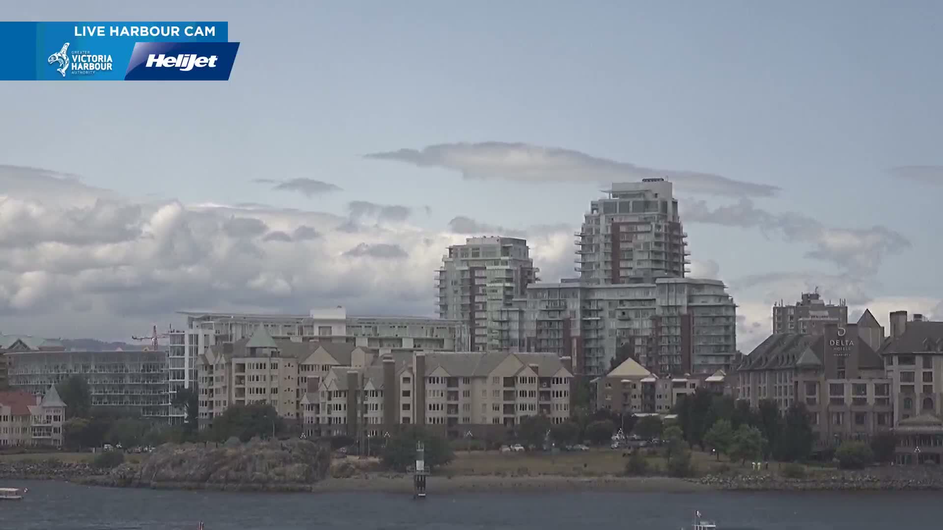 A waterfront view of several multi-story buildings under a partly cloudy sky.