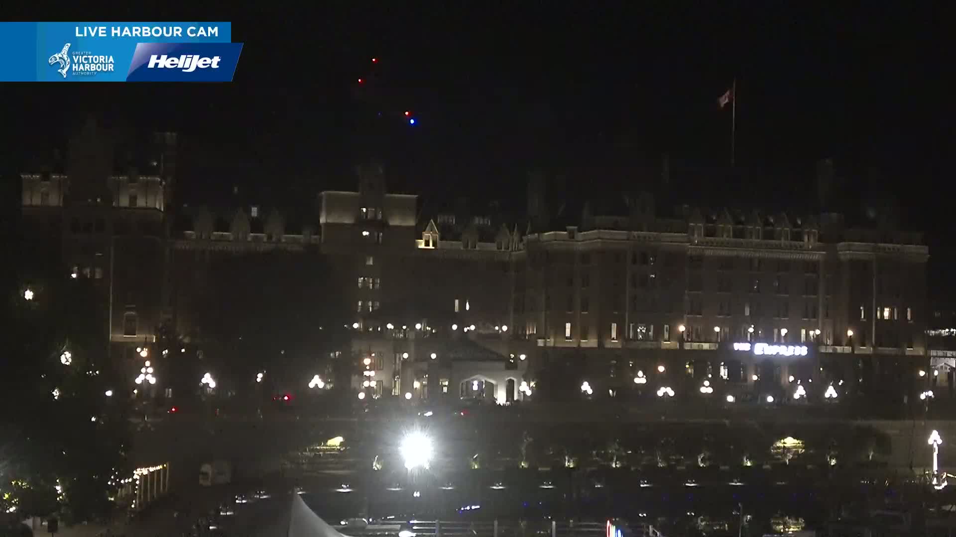 A large, illuminated building stands at night under a clear, dark sky with a few faint lights visible.