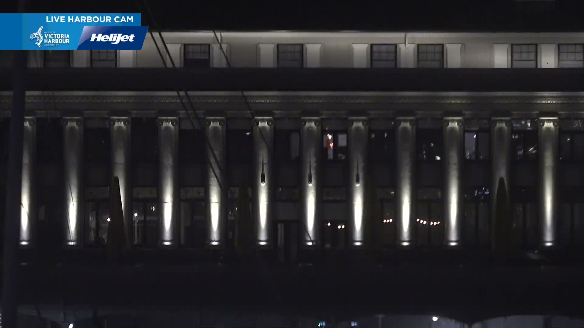 A large building with numerous illuminated columns stands brightly lit against a dark, clear night sky.