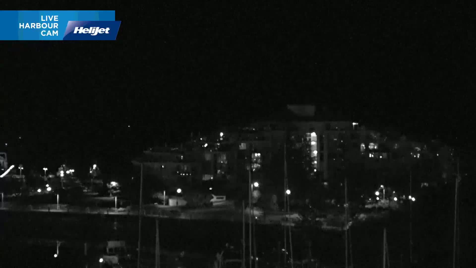 A nighttime, low-light view of a harbor with buildings and boats.