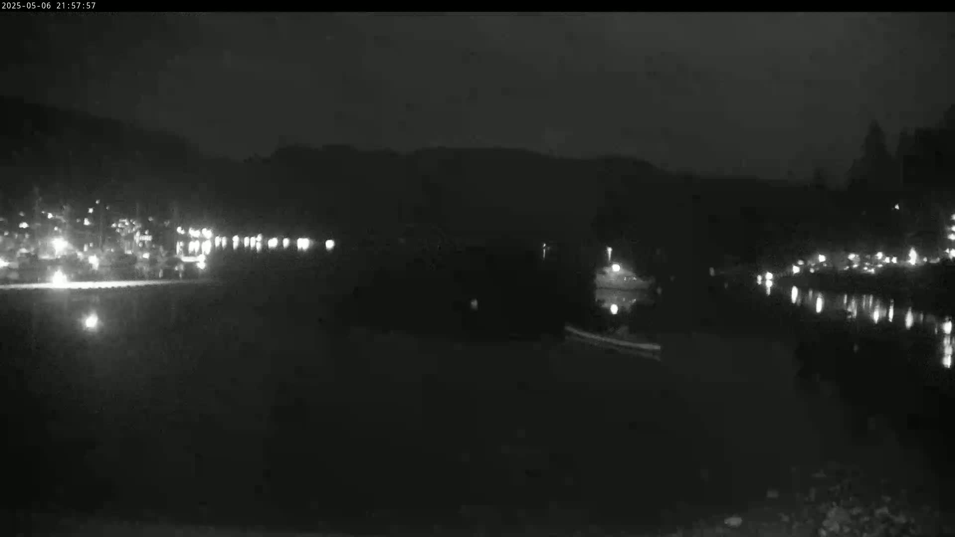A nighttime view of a dark body of water reflecting distant lights from a shoreline at night.