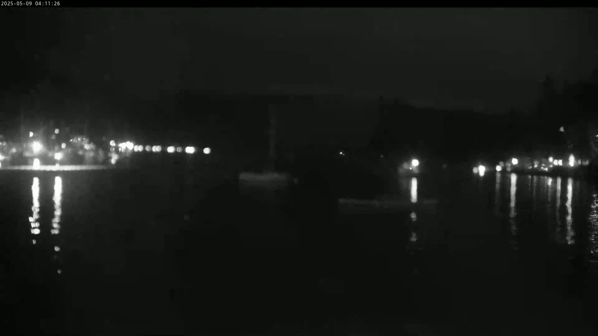 At night, lights from a distant shoreline reflect on calm water.