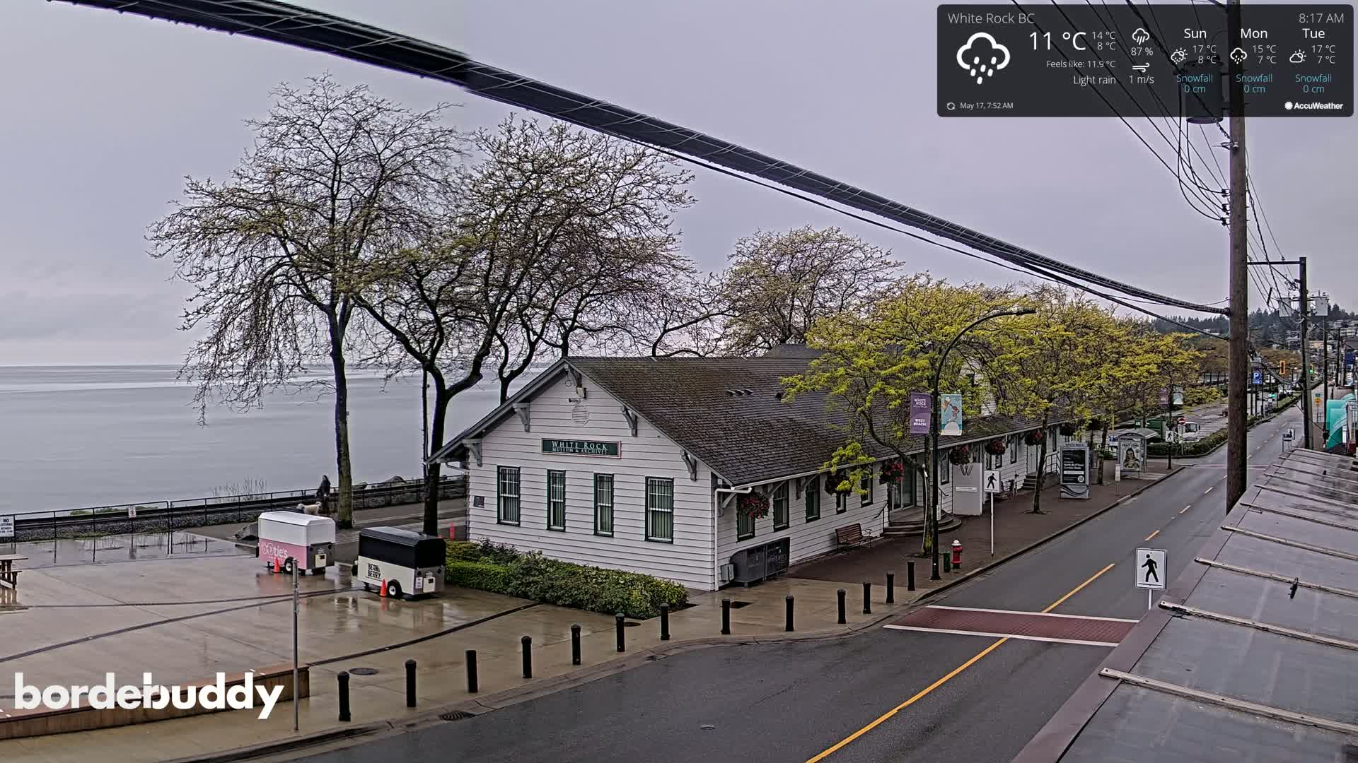 A white building near a calm body of water on an overcast day with light rain.