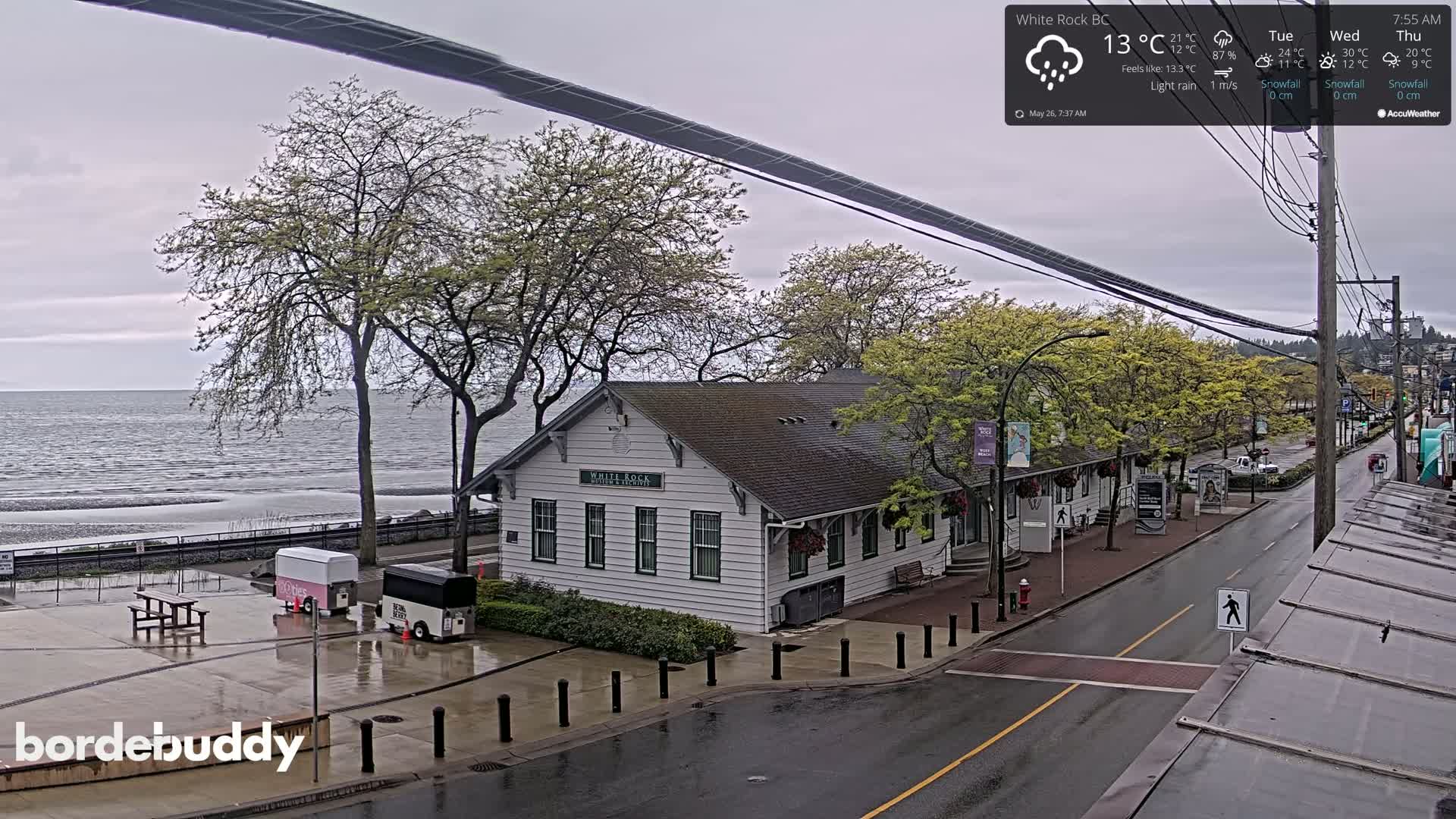 A white building near the ocean is seen on a wet, overcast day.