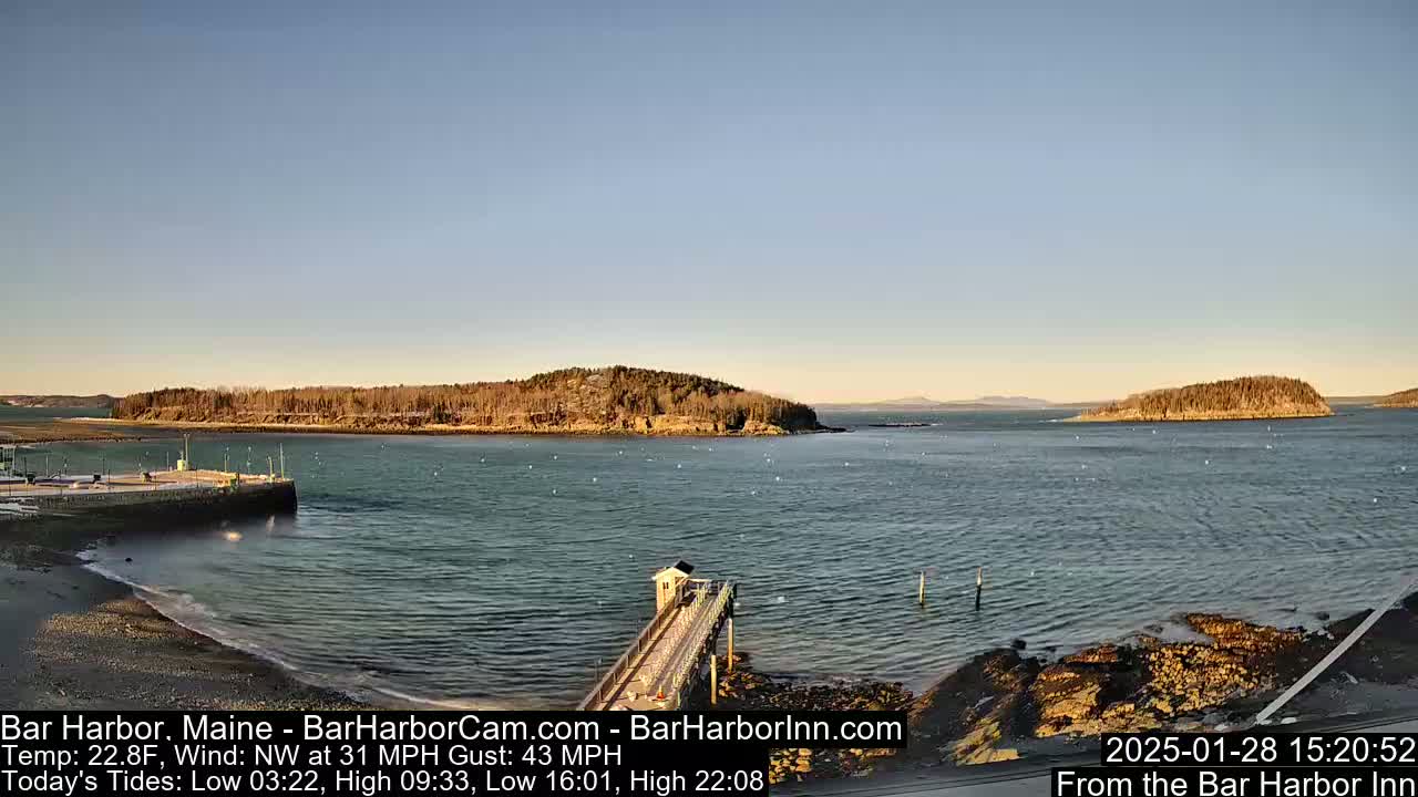 A calm harbor with a small island and a pier under a clear, sunny sky.