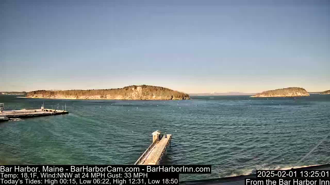 A long pier extends into a calm body of water, with islands and a distant shoreline visible under a clear sky.