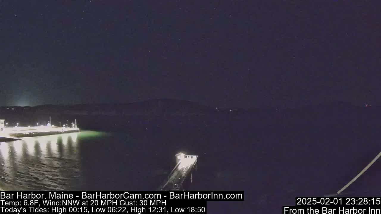 A nighttime view of a pier extending into a dark body of water under a clear, starry sky with a 20 mph northwest wind and gusts up to 30 mph.