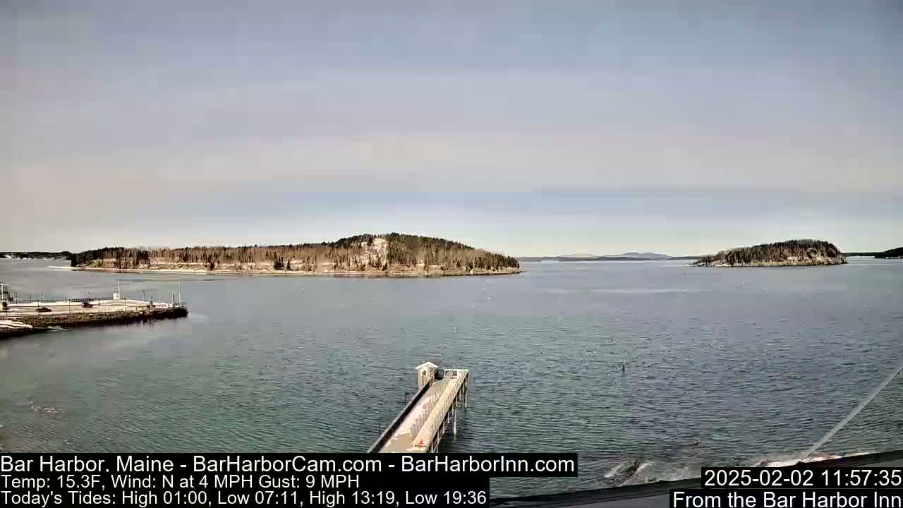 A calm body of water with small islands and a long pier is visible under a mostly clear sky.