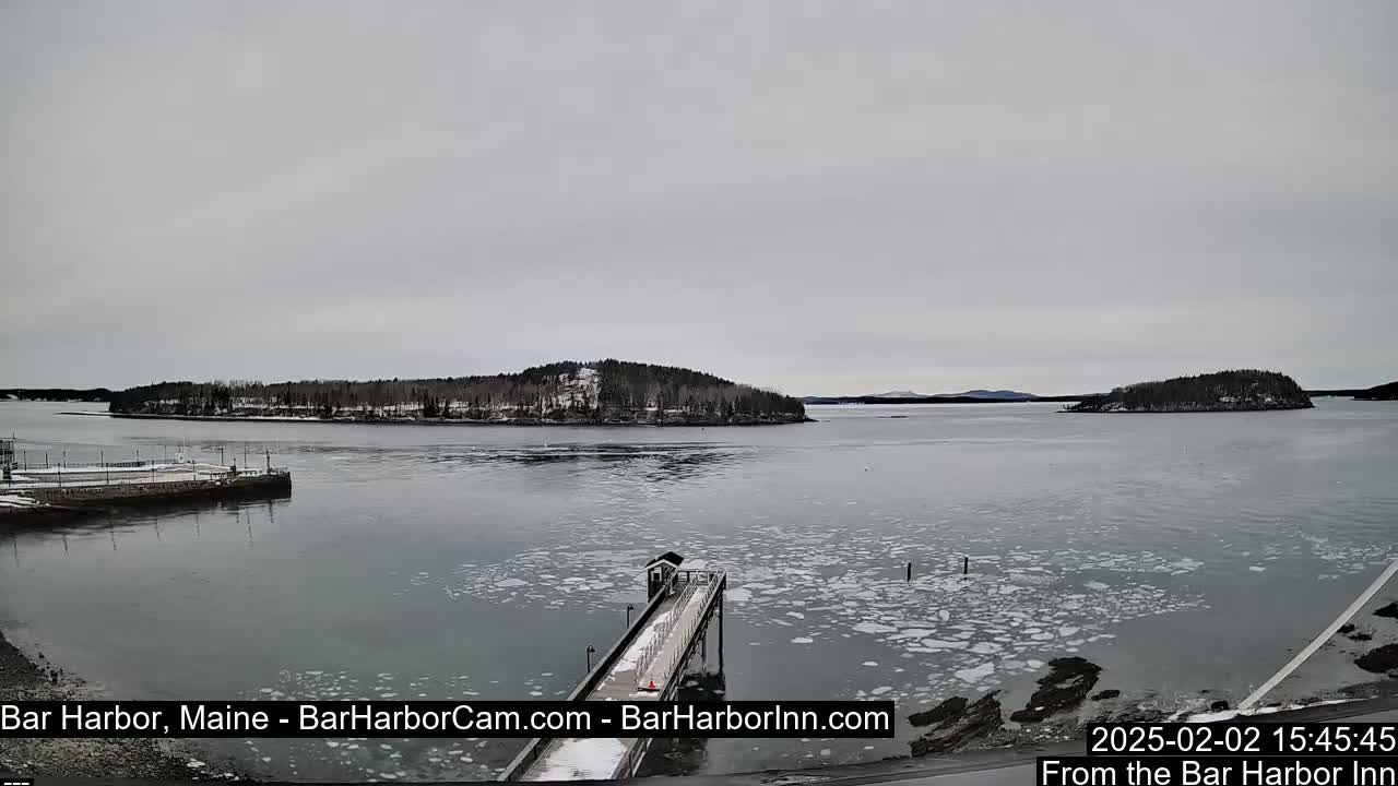 A snow-dusted island and a partially frozen harbor are visible under an overcast sky.