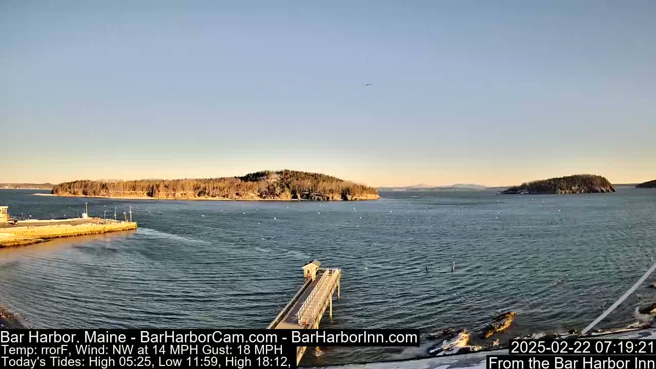 A calm, slightly choppy harbor is seen from a pier on a clear day with a northwest wind.