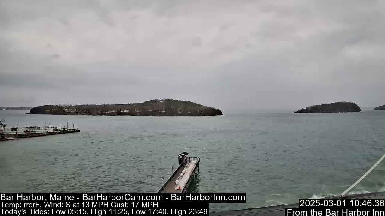 A long pier extends into a choppy gray sea toward small, tree-covered islands under an overcast sky.