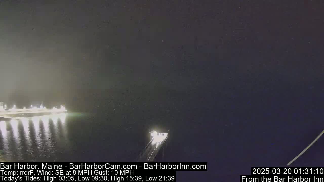A nighttime, low-light view of a pier extending into dark water under a mostly clear sky with a southeast wind.