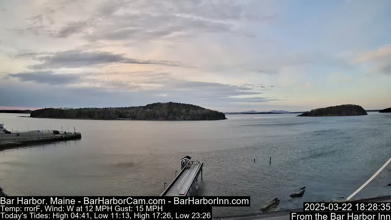 A calm body of water with islands in the distance under a mostly cloudy sky.