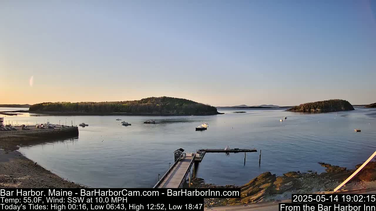 A calm harbor with several boats is viewed from a pier on a partly sunny evening with a light south-southwesterly wind.