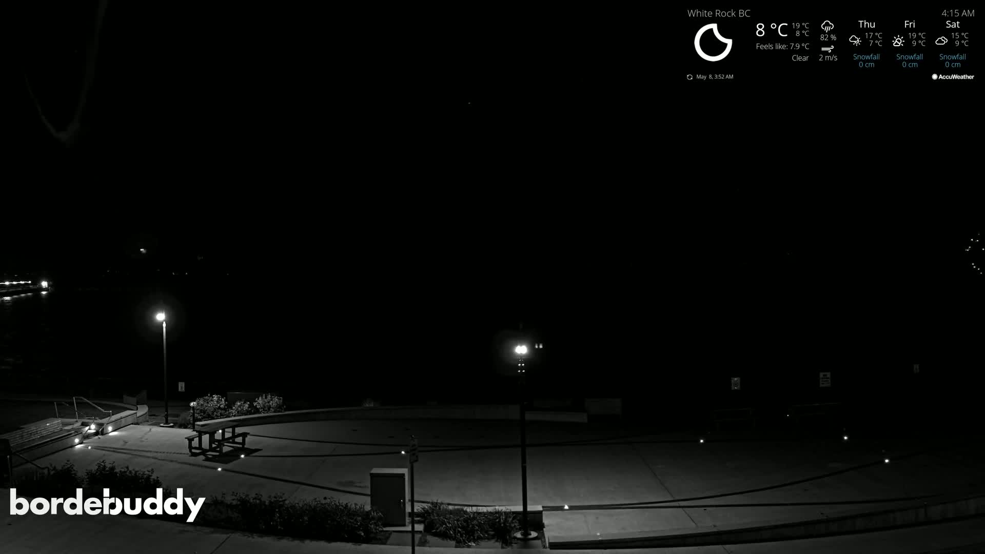 A nighttime, clear-weather view of an empty paved area with a picnic table and several lampposts.
