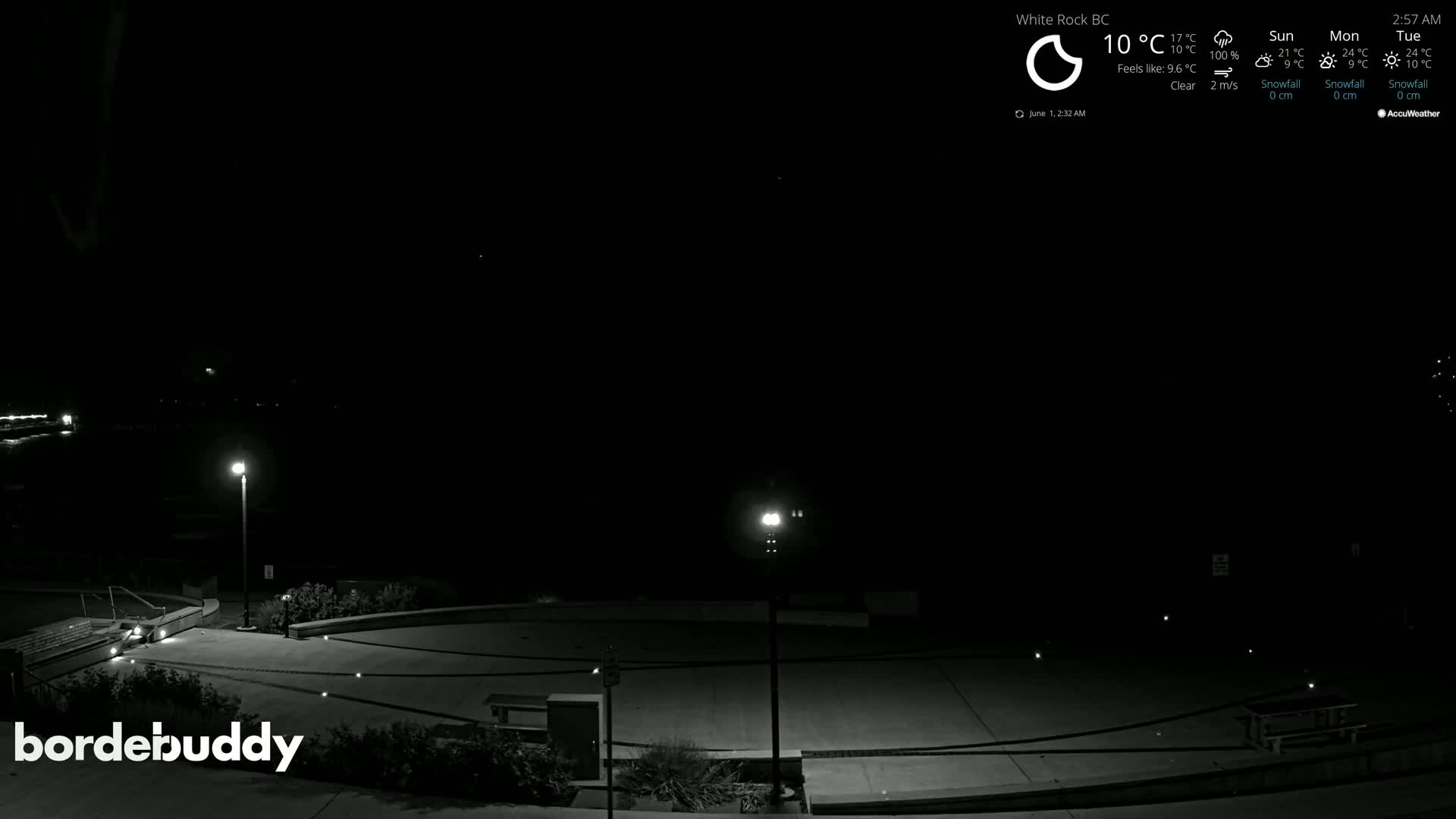 A nighttime, clear-weather view of an empty plaza with several lit lampposts.