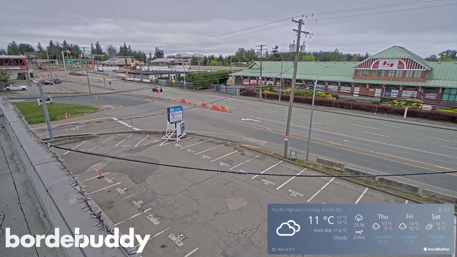 A mostly empty parking lot overlooks a street with sparse traffic and a building under a cloudy sky.