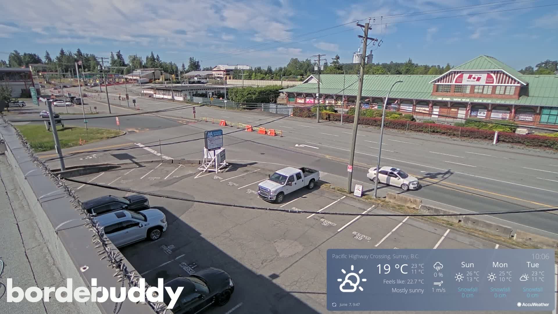 A mostly sunny parking lot and roadway are viewed from an elevated vantage point, with several cars visible.