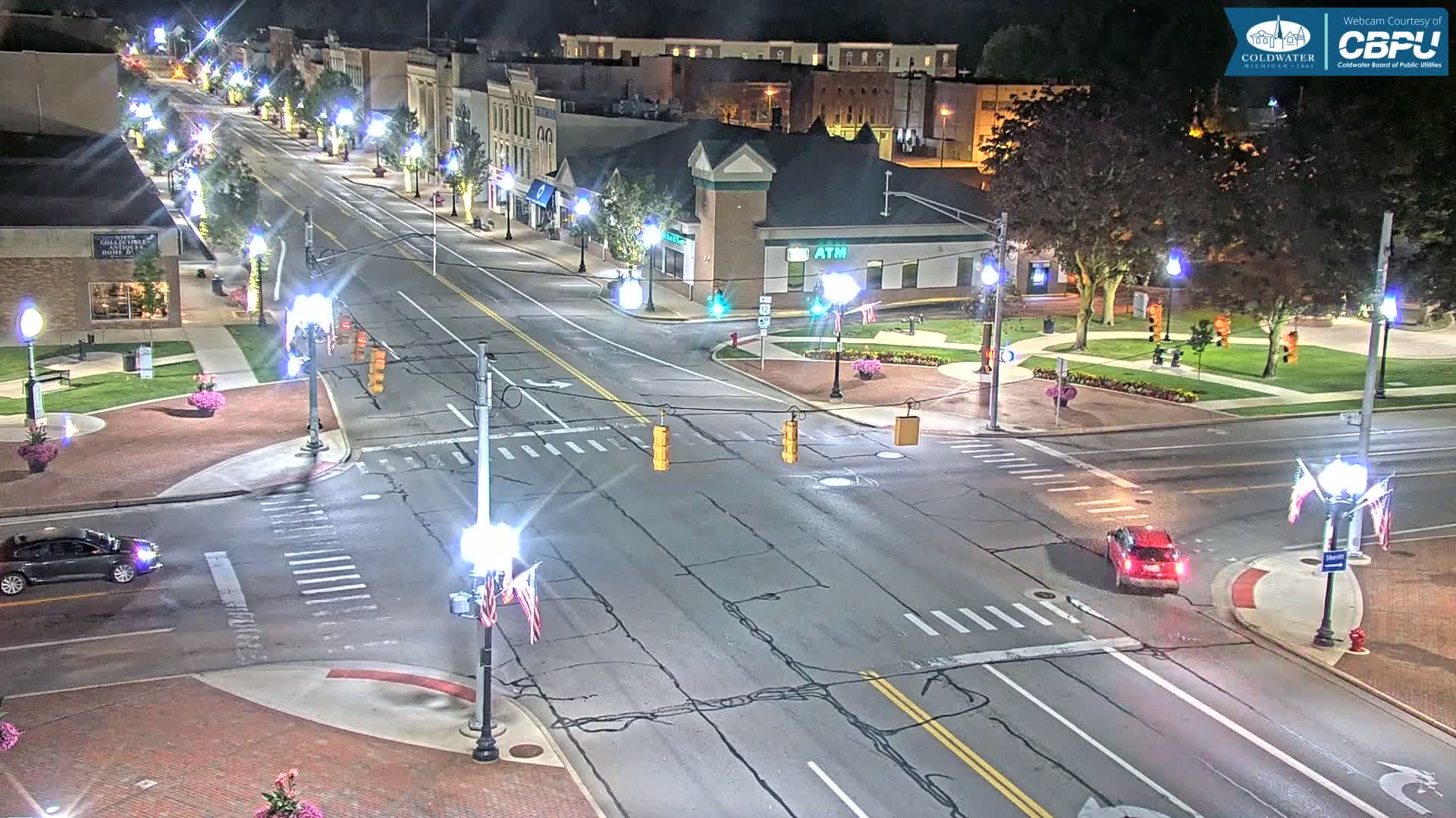 A nighttime view of a town square intersection with several streets and buildings illuminated by streetlights.