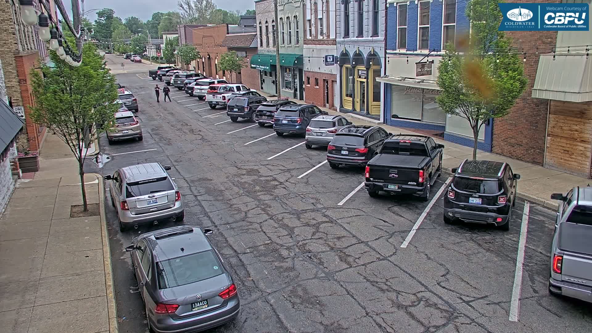 A street lined with parked cars and brick buildings under an overcast sky.