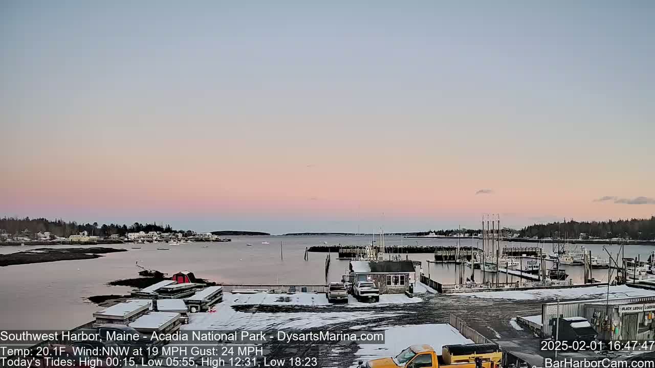 A snow-dusted harbor town is shown at sunset under a pale pink sky with a northwest wind.
