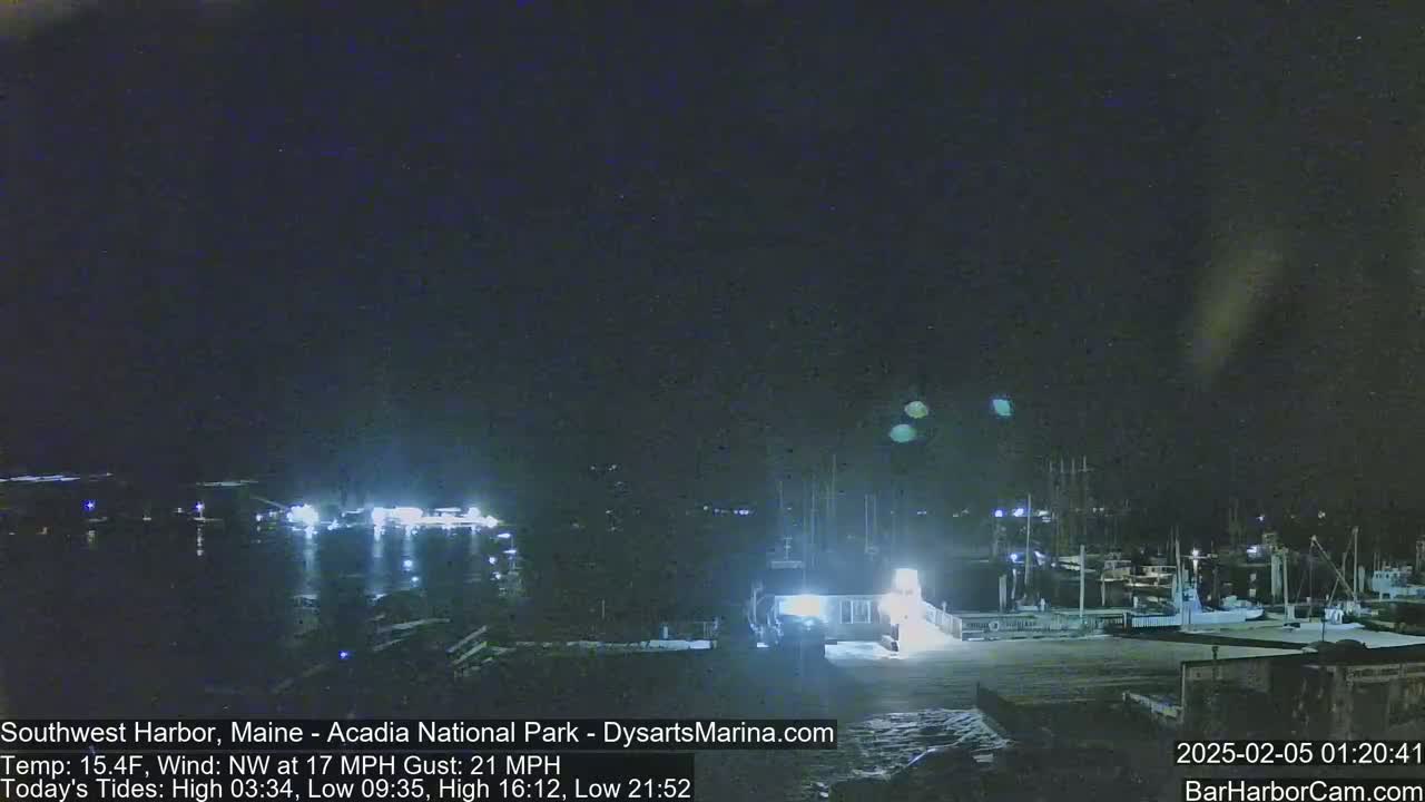 A nighttime harbor scene with numerous boats docked under a dark sky, with a northwest wind at 17 mph and gusts up to 21 mph.