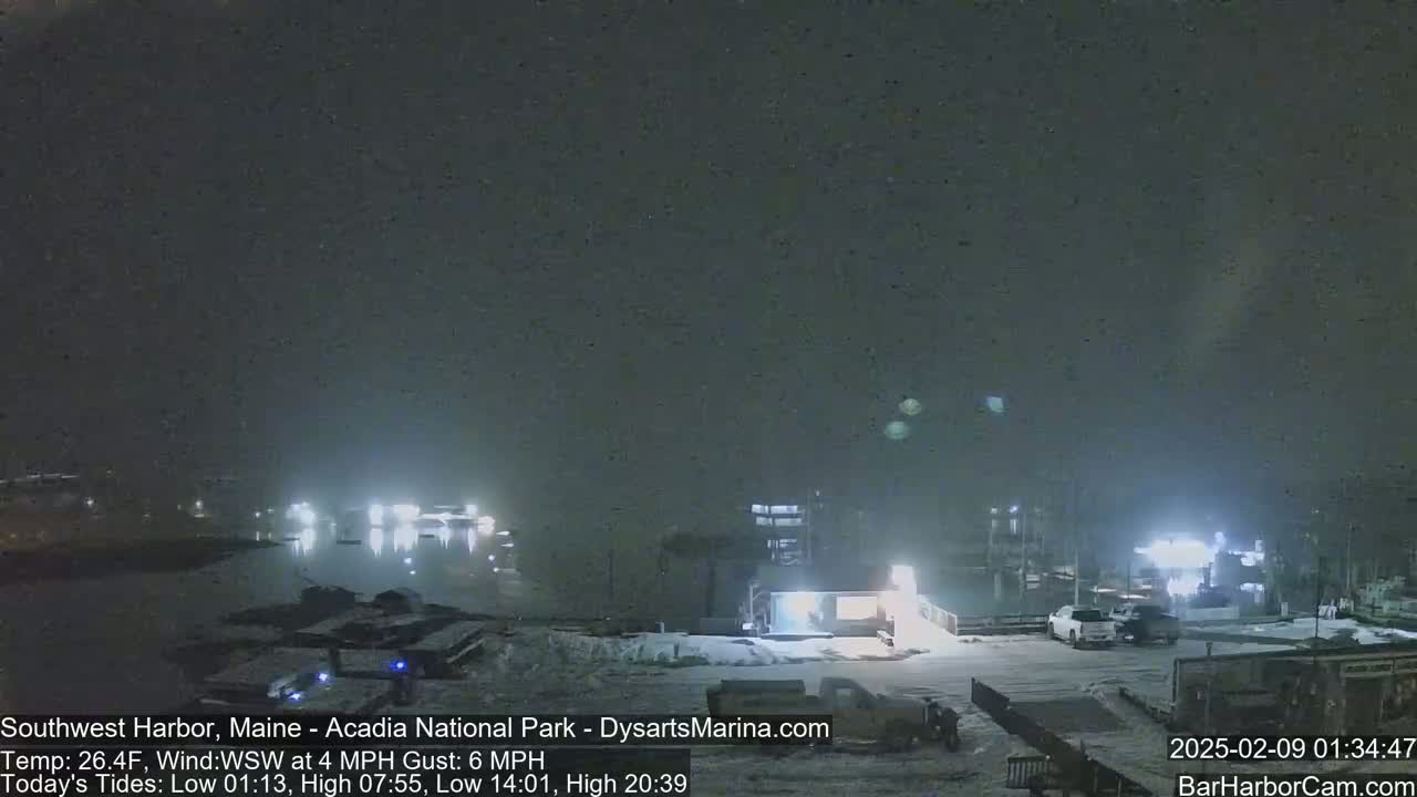 A nighttime scene of a harbor with snow on the ground and a dark, hazy sky.