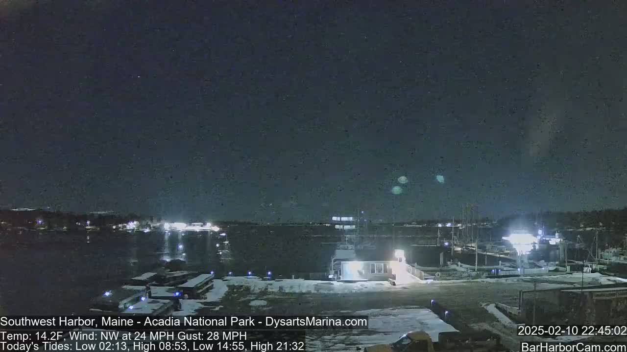 A nighttime view of a snow-covered marina with a dark, starry sky and a northwest wind of 24 mph gusting to 28 mph.