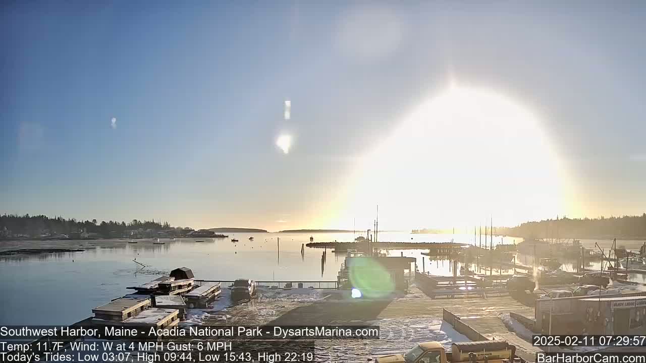 A harbor scene on a sunny, cold day with a few boats moored and light snow on the ground.