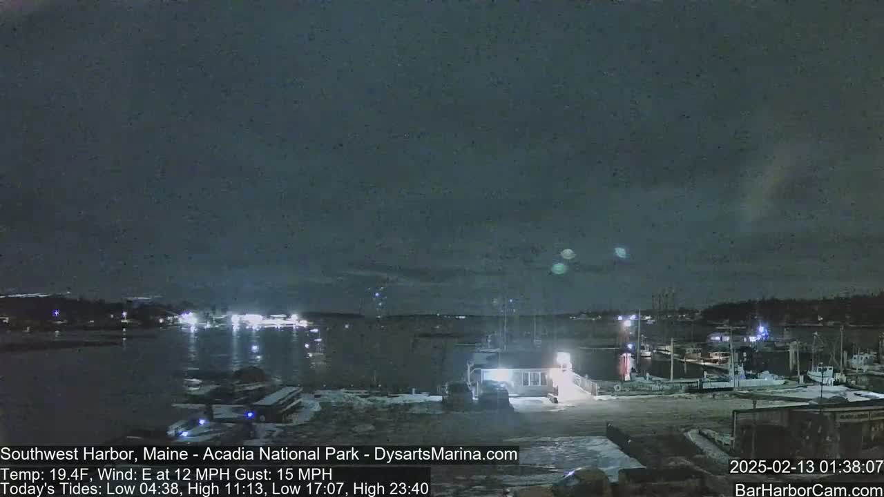 A nighttime view of a harbor with boats docked, under a dark, cloudy sky.