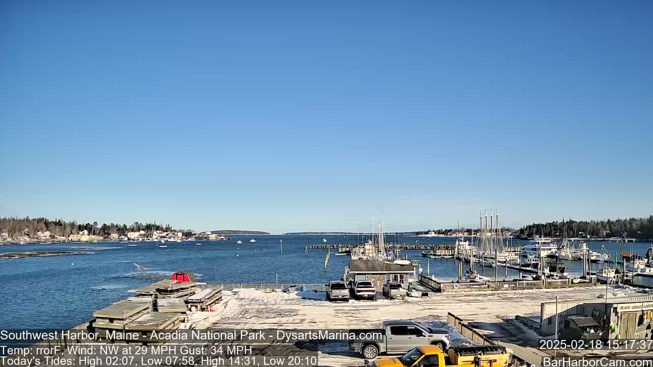 A harbor filled with boats on a sunny day, with some snow on the ground and a northwest wind.