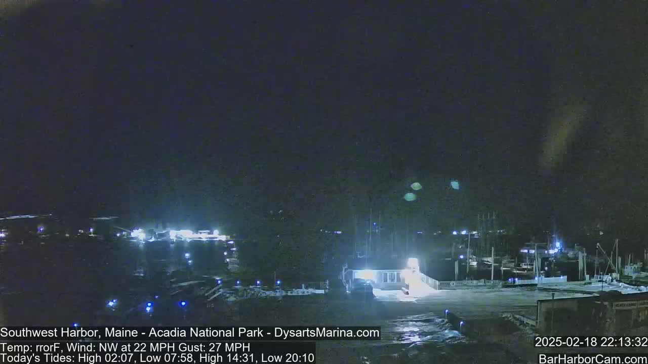 A nighttime view of a harbor with docked boats under a dark sky and a northwest wind.