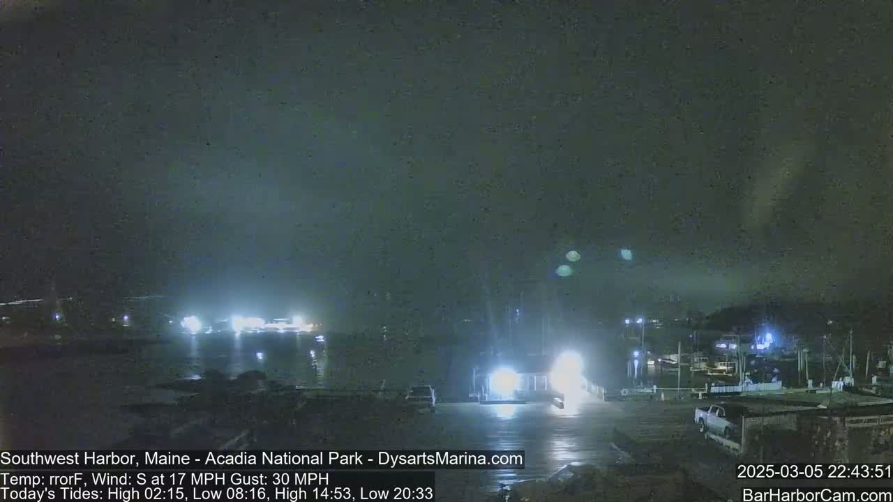 A nighttime harbor scene shows boats moored at a dock under a dark, cloudy sky with a 17 mph south wind gusting to 30 mph.