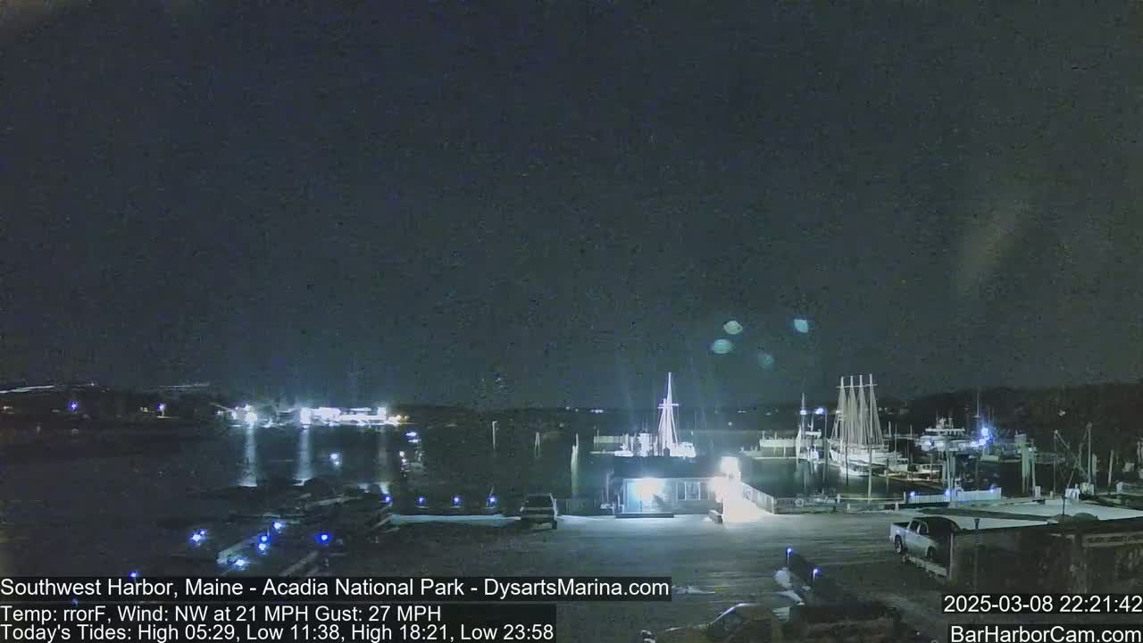 A nighttime harbor scene with several boats docked under a dark, clear sky, a northwest wind at 21 mph with gusts up to 27 mph.