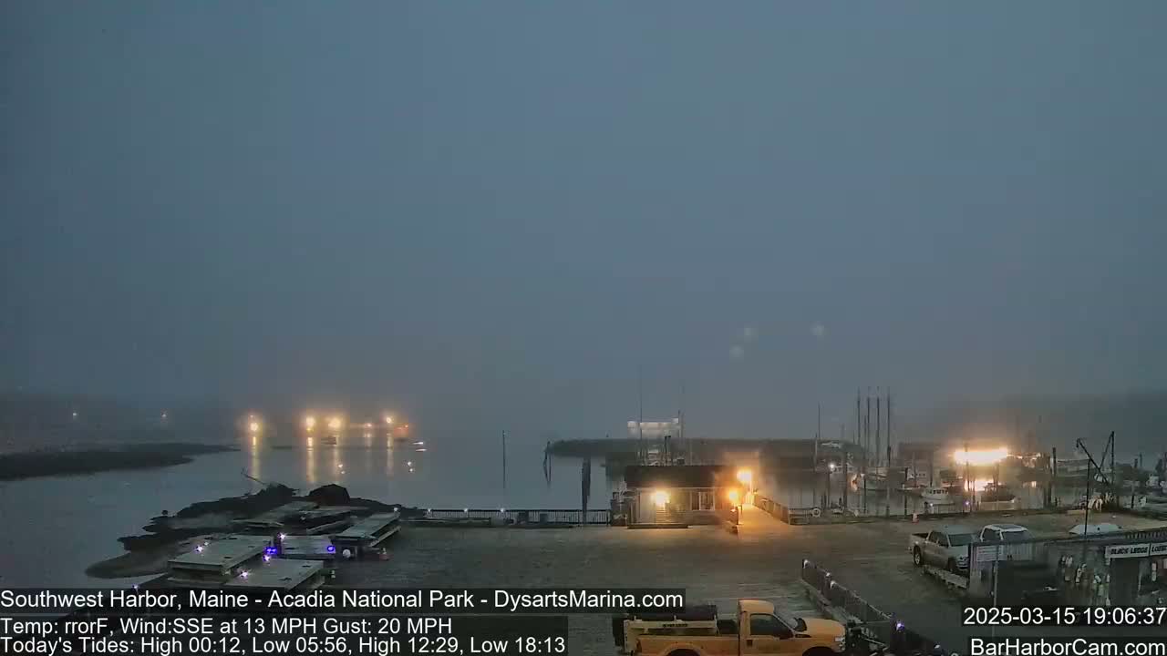 A foggy harbor at night, with lights illuminating boats and a marina.