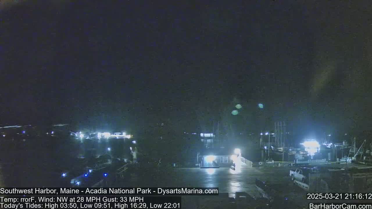 A nighttime harbor scene with boats moored, under a dark sky with a northwest wind.